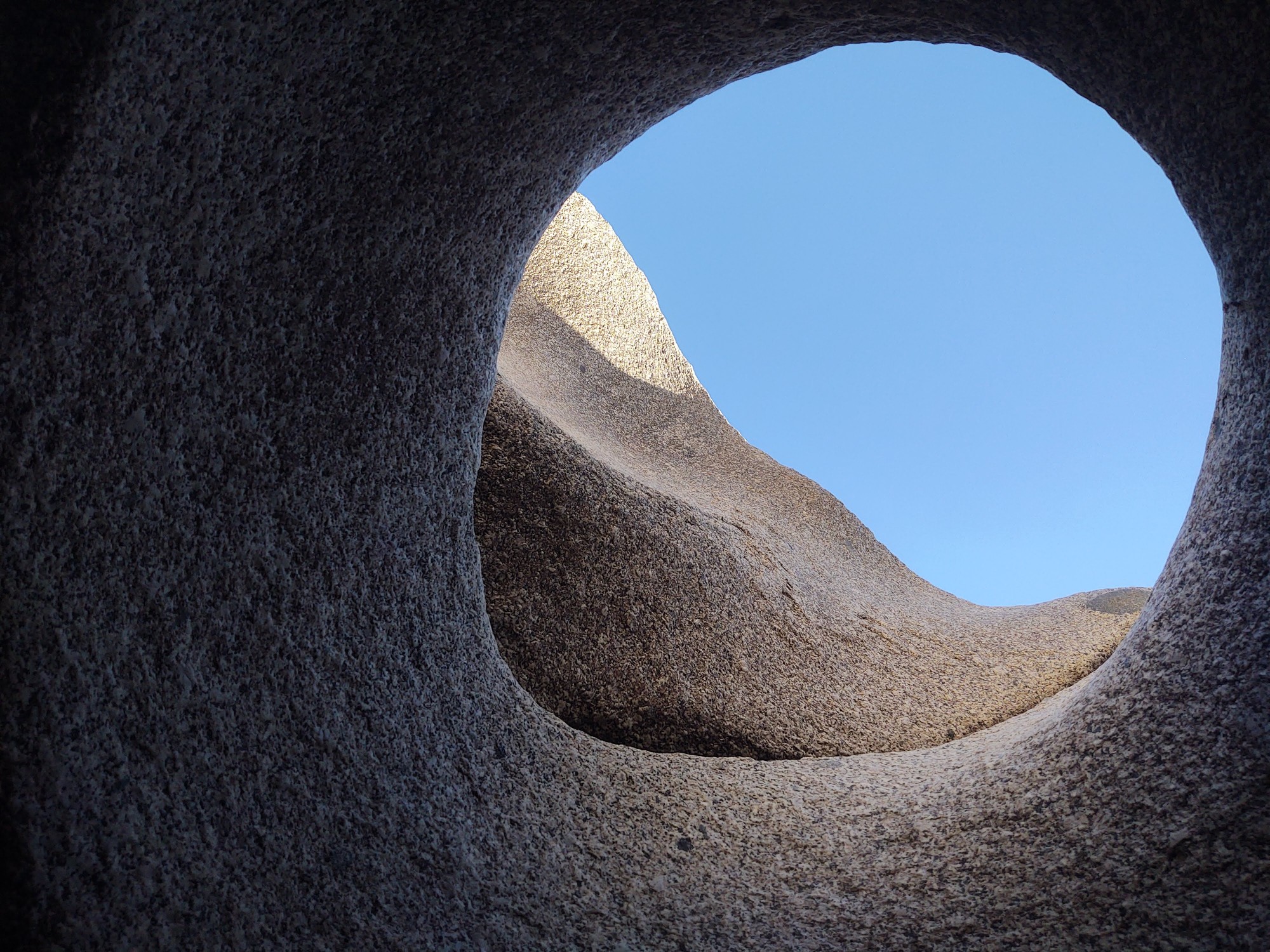 Looking up through an opening in granite to a blue sky
